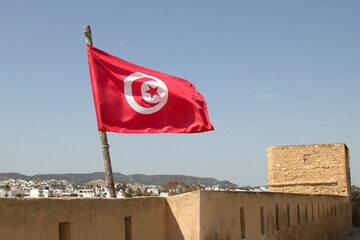 Tunisian National Flag flying from the Old Medina in Hammammet. The crescent and star depicted on the flag of Tunisia are traditional symbols of Islam, and are also considered symbols of good luck.