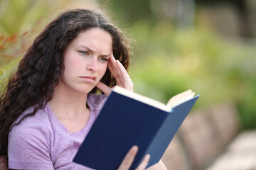 Confused woman reading a paper bad book in a park