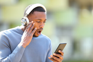 Shocked man with headphones and phone in the street