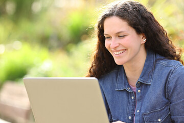 Happy woman using laptop in a park