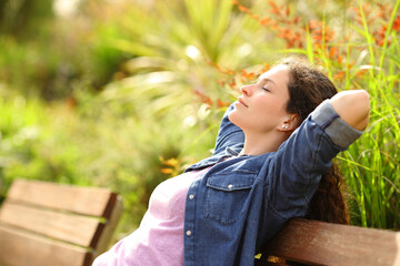 Woman relaxing and resting sitting in a bench in a park