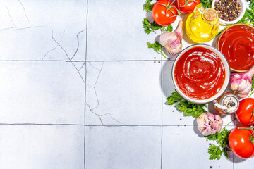 Homemade ketchup sauce. Two bowl with tomato ketchup red sauce with ingredient for cooking - herbs, raw fresh tomatoes, olive oil, garlic, salt, spices, on white tiled background top view copy space