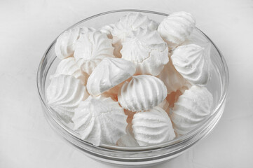 glass vase with French meringue dessert on a gray background close-up.