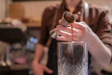 copo de Negroni sendo feito por barman.