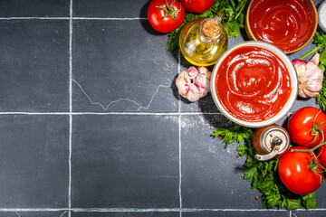 Homemade ketchup sauce. Two bowl with tomato ketchup red sauce with ingredient for cooking - herbs,...