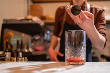 copo de Negroni sendo feito por barman.