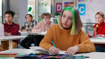Fototapeta Teenage schoolgirl with green hair writing test in class in school obraz