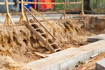 Descent into a deep pit during the construction of a house. Building safety. Ladder for descending...