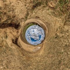 blue sphere little planet inside yellow sand field background. curvature of space