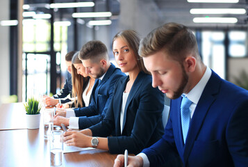 Smiling businesswoman looking at camera at seminar with her colleagues near by