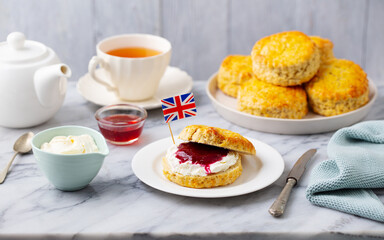 Scones, tea cakes with jam, clotted cream with the flag of Great Britain. Traditional British teatime. Grey background. - 506370027