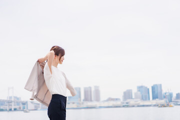 都会でジャケットを脱ぐビジネスウーマン