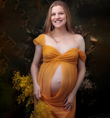 Young beautiful redhead woman pregnant and expecting a baby over flowers background with happy and cool smile maternity wearing a chiffon pregnancy dress Lucky person. touching belly