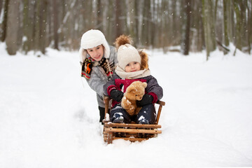 Fototapeta na wymiar Children on a wooden sled on a winter day. Active winter kids outdoors games