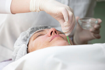 Close-up of a cosmetologist doctor doing an anti-aging procedure, mask and peeling to an elderly client in a beauty clinic. Skin care specialist. Cosmetology age.