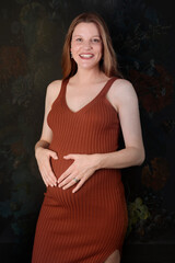 Young beautiful redhead woman pregnant expecting baby over isolated black background with a happy and cool smile Lucky person. touching belly