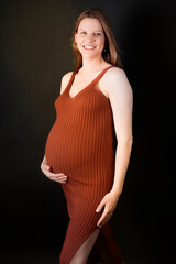 Young beautiful redhead woman pregnant and expecting baby over isolated black background with a happy and cool smile Lucky person. touching belly