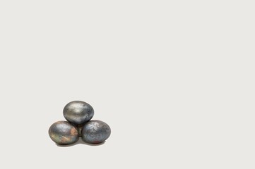 Easter eggs festively painted in vintage dark paint are stacked in a small pyramid on a white banner background.