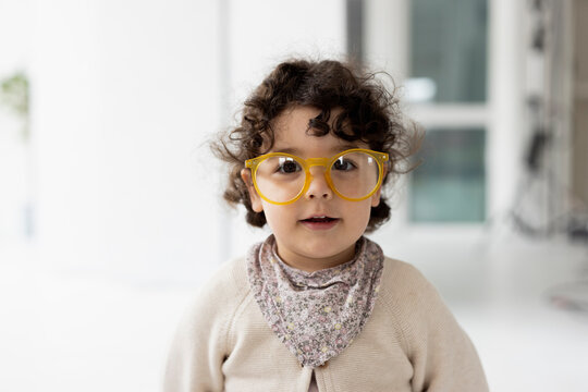 Cute little girl wearing oversized eyeglasses looking at camera