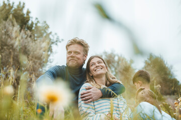 Smiling man with arm around woman sitting in meadow