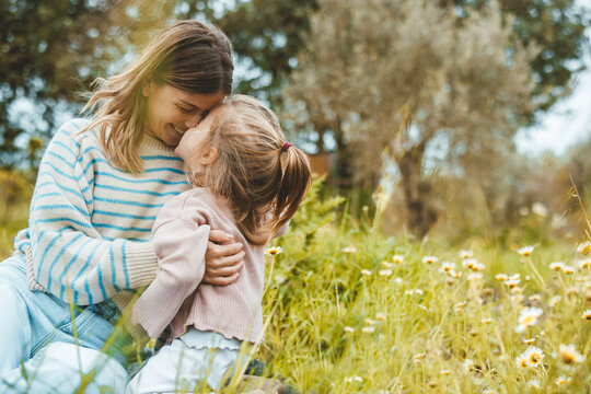 Happy mother and daughter rubbing noses in meadow