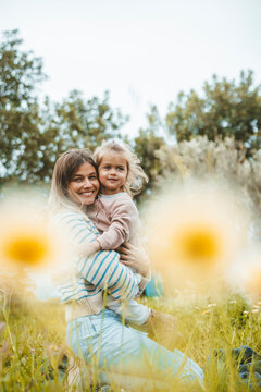Happy woman embracing daughter in meadow