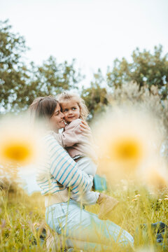 Smiling woman embracing daughter in meadow