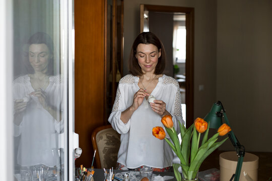 Smiling mature woman sculpting dolls face at table
