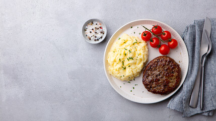 Beefsteak with mashed potato on a plate. Grey background. Copy space. Top view.