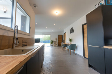 Intérieur d'une maison neuve, vue depuis la cuisine, mur blanc et éléments en noir