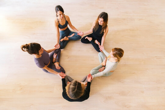Women sitting in lotus position meditating at yoga studio