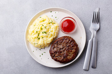 Beefsteak with mashed potato on a plate. Grey background. Close up. Top view.