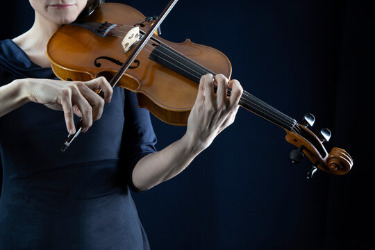 Mature woman playing violin in front of black background