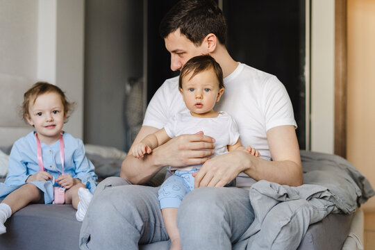 Man with son and daughter sitting on bed at home