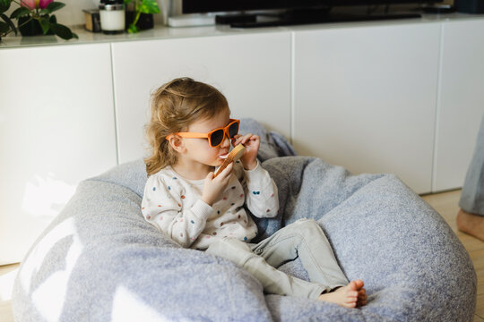 Cute girl eating bread sitting on bread at home in morning