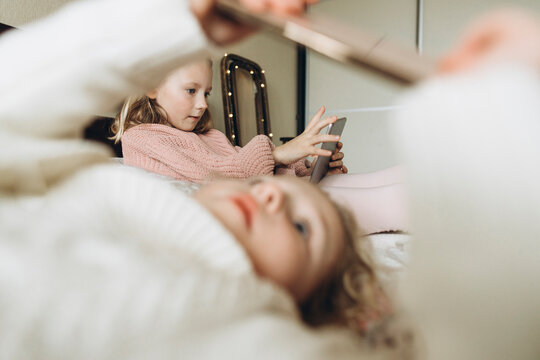Girls using smart phones in bedroom at home