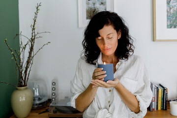 Woman with eyes closed holding candle in living room at home