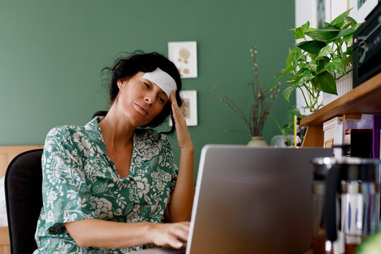 Overworked businesswoman suffering from headache using laptop at home