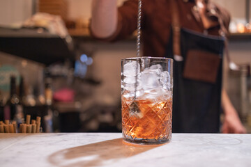 copo de Negroni sendo feito por barman.
