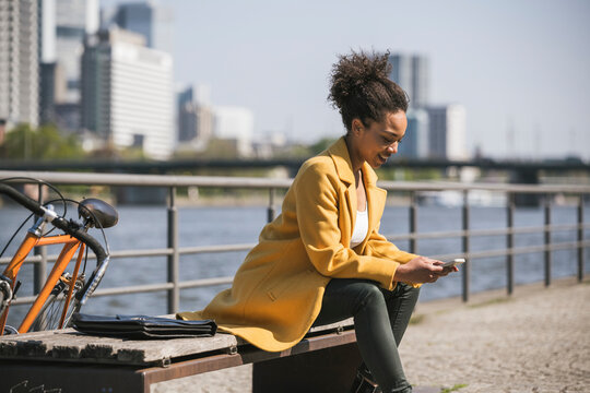 Businesswoman text messaging over smart phone on sunny day