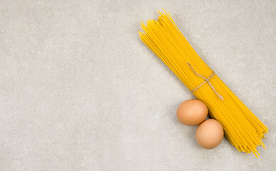 Fresh noodles spaghetti with eggs on gray background