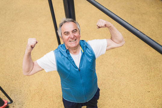 Confident senior man flexing muscles at park