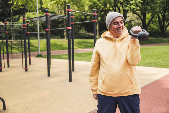Smiling senior man exercising with kettlebell at park