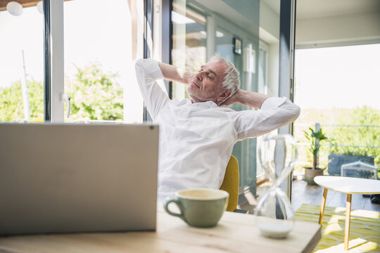 Businessman with hands behind head relaxing at home