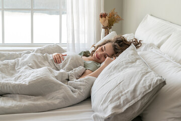 Smiling young woman sleeping in bed at home