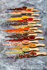 A set of spices on a gray background. Variety of spices from India. Food decoration design. Various spices, peppers and herbs close-up top view. Set of peppers, salt, herbs and spices for cooking.