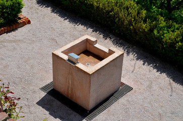 The square stone fountain serves as a washbasin in the park or on the garden terrace. people can...