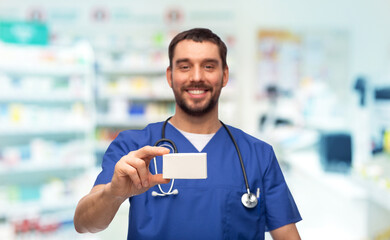 healthcare, profession and medicine concept - happy smiling doctor or male nurse in blue uniform...