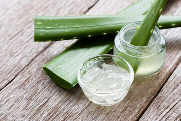 Fresh aloe vera leaf and vera gel on rustic wooden table background. 