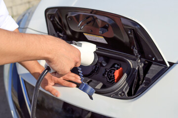 Close-up of male hands connect an electric car to a charger